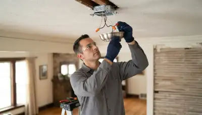 Chicago, IL electrician installing a ceiling light fixture and connecting wiring at the ceiling box