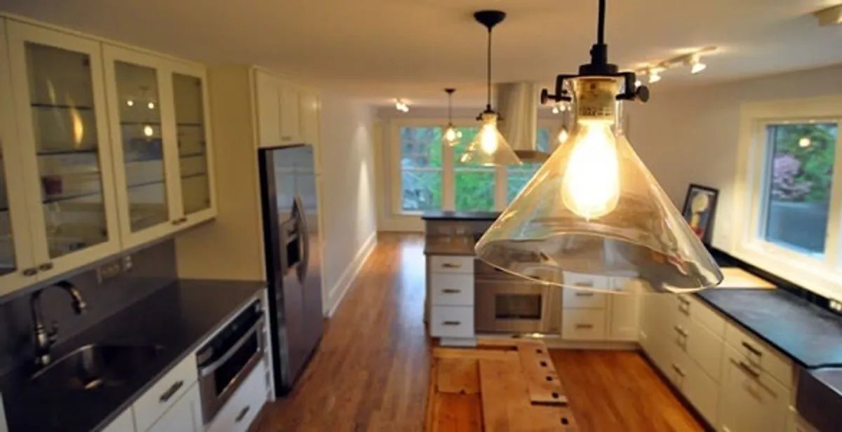 Residential electrician installing modern indoor light fixture in a home in Chicago, IL