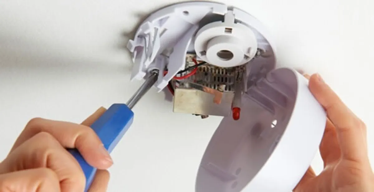 Certified technician wiring smoke detector during installation in Chicago, IL